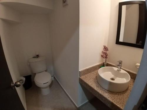 a bathroom with a sink and a toilet and a mirror at Hermosa Casa Vacacional Puerto Morelos in Puerto Morelos