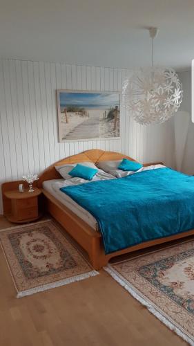 a bedroom with a bed with blue sheets and a chandelier at Ferienwohnung "Am Johannisberg" in Witzenhausen