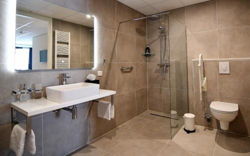 a bathroom with a sink and a toilet and a shower at Hotel Brasserie de Kaai in Steenbergen