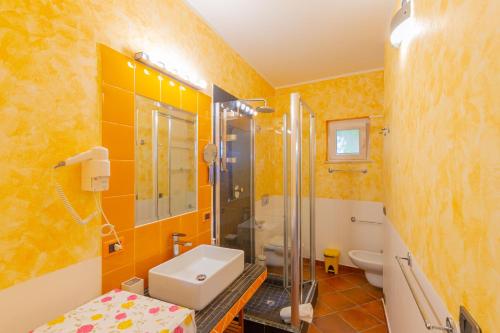 a bathroom with yellow walls and a sink and a shower at Residence Agape in Cefalù