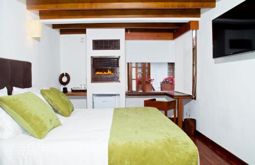 a bedroom with a white bed and a fireplace at Hotel Casona Usaquen in Bogotá