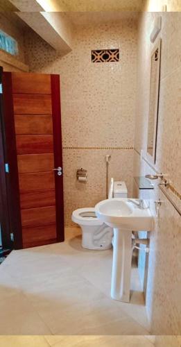 a bathroom with a toilet and a sink and a door at hotel Casa do Francês na Praia in Boa Vista