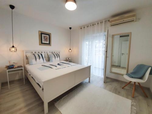 a white bedroom with a large white bed and a chair at Viva Zadar in Zadar