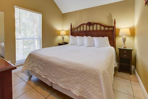 a bedroom with a large bed with white sheets and a window at Nantucket Rainbow Cottages in Destin