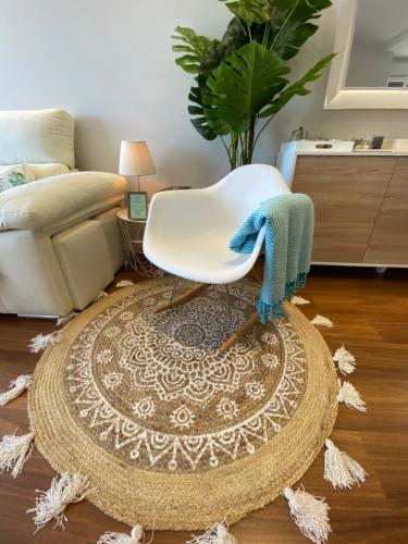 a white chair sitting on a rug in a living room at Playa Granada Apartamentos Moriscos II in Motril