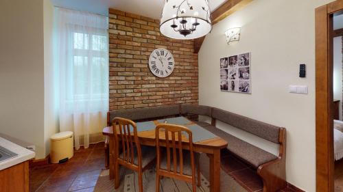 une salle à manger avec une table, des chaises et une horloge dans l'établissement Apartmán Marta, 200 m Ski Tatranska Lomnica, à Tatranská Lomnica