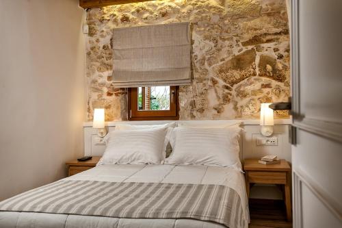 a bedroom with a bed and a stone wall at Casa di Gouto in Chania