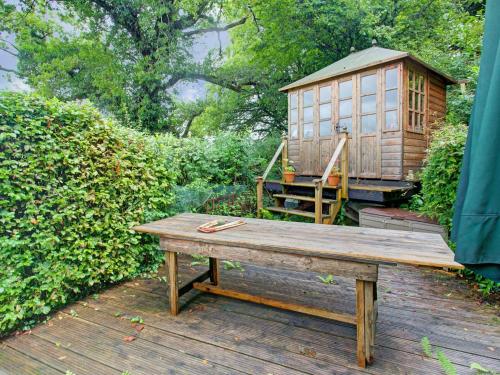 un banc en bois à côté d'une petite maison sur une terrasse dans l'établissement Hill view Holiday Home with Garden, à Taunton