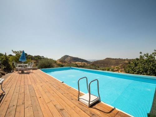a swimming pool on a wooden deck with mountains in the background at Belvilla by OYO Modern villa in Nissoria with pool in Nissoria
