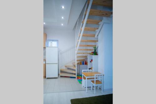 a room with a staircase and a table and a refrigerator at Günter Vendégház-Hajdúnánás in Hajdúnánás