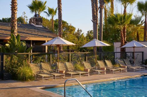 a row of chairs and umbrellas next to a swimming pool at The Capri Hotel in Ojai