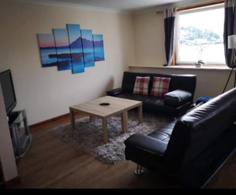 a living room with a couch and a coffee table at Panoramic Harbour View Apartment in Oban