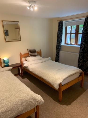 Duas camas num quarto com um espelho e uma janela em The Loft at Duffryn Mawr Self Catering Cottages em Hensol