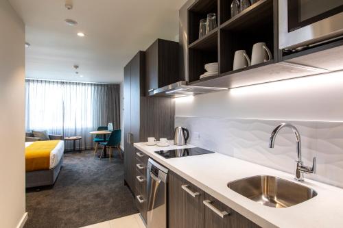 a kitchen with a sink and a bed in a room at Quest Palmerston North in Palmerston North