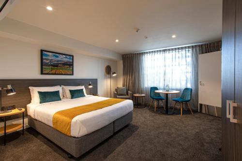 a hotel room with a bed and a table and chairs at Quest Palmerston North in Palmerston North