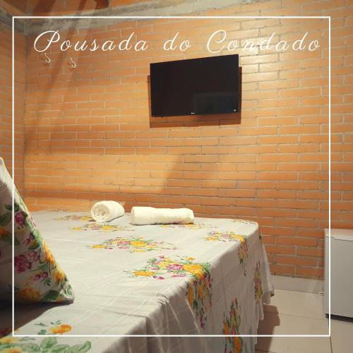 Zimmer mit einem Bett und einem TV an einer Backsteinwand in der Unterkunft Pousada do Condado in Paraty