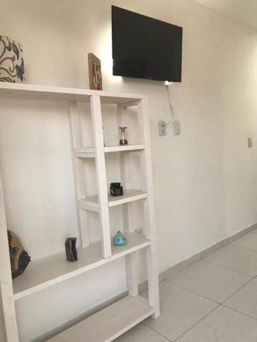 a white book shelf with a tv on a wall at AYRE GOSTOSO POUSADA in São Miguel do Gostoso