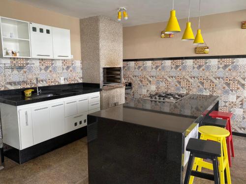 a kitchen with white cabinets and a black counter top at Residencial Lúpulos in Angra dos Reis