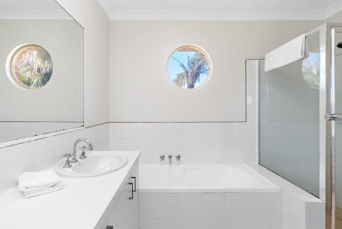 a white bathroom with a sink and a shower at Bayside Court Apartments in Byron Bay