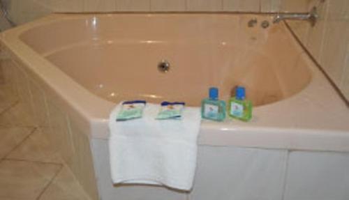 a bath tub with two towels and two bottles on it at Nunawading Motor Inn in Nunawading