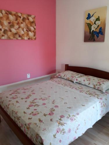 a bedroom with a bed with a floral bedspread at Suites Manu in Ilhabela