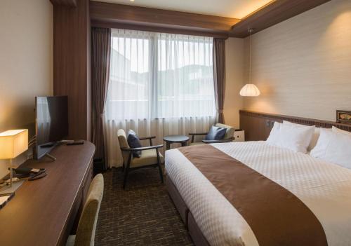 a hotel room with a bed and a desk at Kowakuen Haruka in Matsuyama