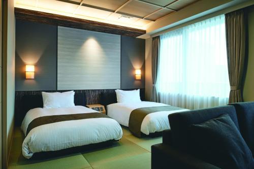 a hotel room with two beds and a window at Kowakuen Haruka in Matsuyama
