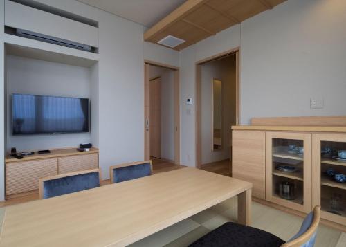a dining room with a table and chairs and a tv at Kowakuen Haruka in Matsuyama