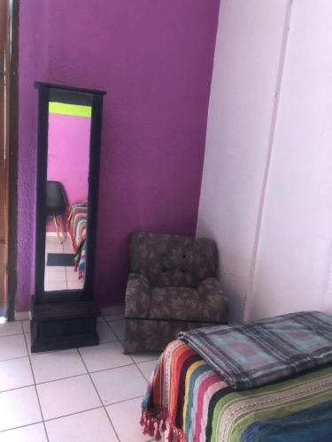 ein Schlafzimmer mit lila Wänden, einem Stuhl und einem Spiegel in der Unterkunft Iguana Hostel Oaxaca in Oaxaca de Juárez