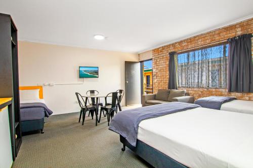 a hotel room with a bed and a table and chairs at River Street Motel in Ballina