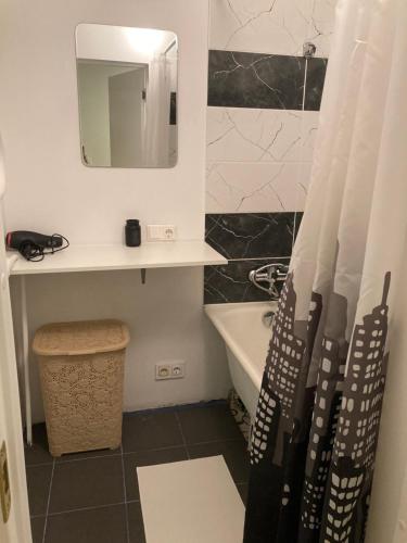 een badkamer met een wastafel, een bad en een spiegel bij apartamenti Zirnis in Cēsis