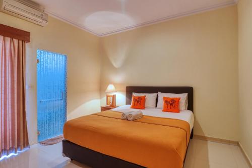 ein Schlafzimmer mit einem Bett mit orangefarbenen Kissen und einem Fenster in der Unterkunft Nibugi Guest House in Nusa Penida