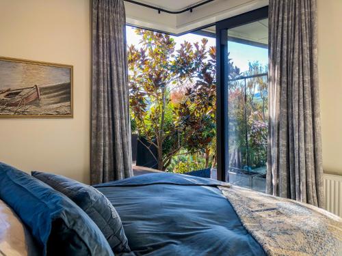 a bedroom with a bed and a large window at Newton Heights in Akaroa