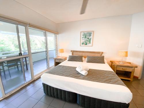 a bedroom with a large bed and large windows at Beach Terraces in Port Douglas