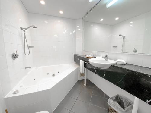 een badkamer met een bad, een wastafel en een bad bij Beach Terraces in Port Douglas