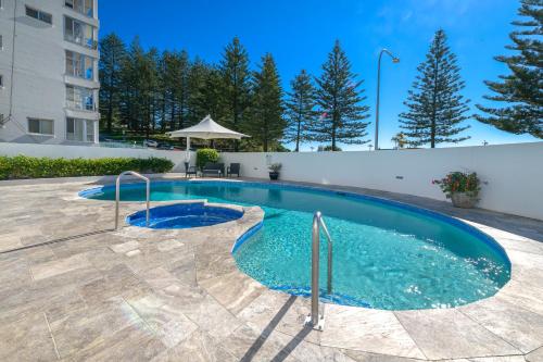 a swimming pool with blue water in a yard at Bayview Apartments Rainbow Bay in Gold Coast