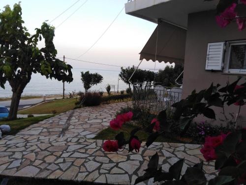 a stone walkway with pink flowers on the side of a house at Akrothalassia in Ligia