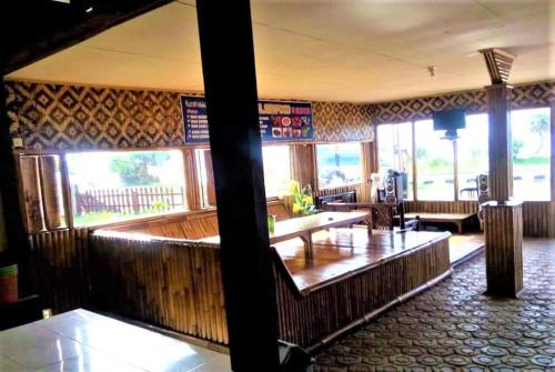 ein Restaurant mit einer Bar mit Holzwänden und Fenstern in der Unterkunft Penginapan Erbysa in Mancagahar