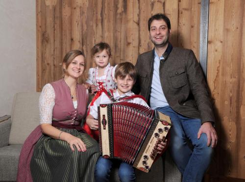 a family posing for a picture with an accordion at Hotel Rose in Mayrhofen