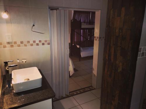 a bathroom with a white sink and a mirror at AAA Rose Garden Guesthouse in Naboomspruit