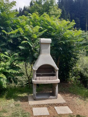 a stone oven sitting in front of some trees at Apartma LUPIS in Podvolovljek