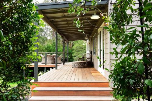 a porch with awning and a bench on a house at Maple Cottage in Kangaroo Valley