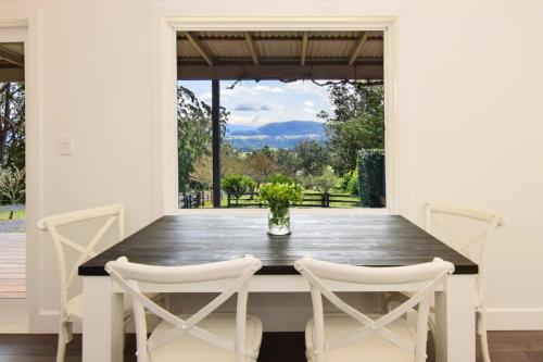 a dining room with a wooden table and chairs at Maple Cottage in Kangaroo Valley
