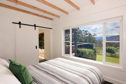 - une chambre avec un lit et une grande fenêtre dans l'établissement Maple Cottage, à Kangaroo Valley