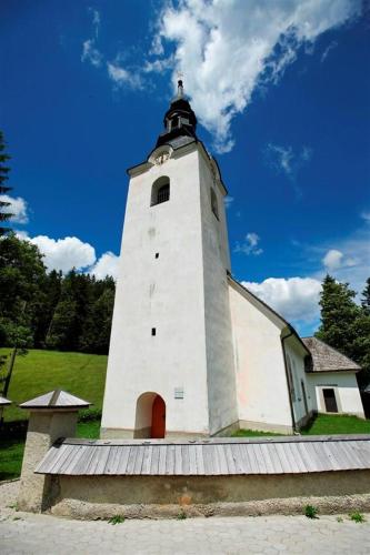 a white tower with a clock on top of it at Apartma LUPIS in Podvolovljek