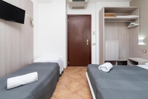 a hotel room with two beds and a television at Casa Betania in Pisa