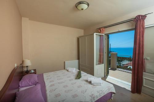 a bedroom with a bed and a balcony with the ocean at LOURDAS BEACH VIEW VILLA in Kefallonia