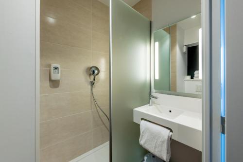 a bathroom with a shower and a sink and a mirror at B&B HOTEL Ouistreham in Ouistreham