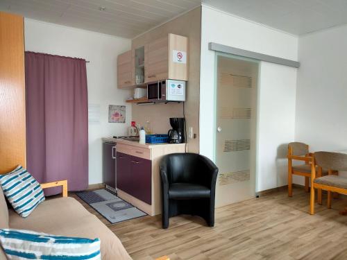 ein kleines Zimmer mit einer Küche, einem Sofa und einem Stuhl in der Unterkunft Monteurzimmer mit Singleküche in Kaufing