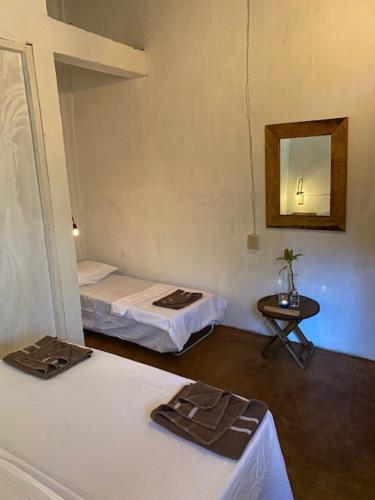 a room with two beds and a mirror and a table at HOSTAL CASA DEL ANGEL in Mazunte